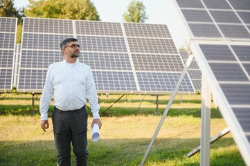 Industrial senior man engineer walking through solar panel field for examination