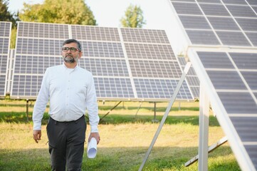 Senior male engineer inspects solar panels on farm. Clean energy.