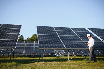 Solar power plant. Man standing near solar panels. Renewable energy