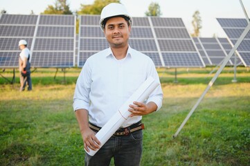 Portrait of Young indian male engineer standing near solar panels, with clear blue sky background, Renewable and clean energy. skill india, copy space