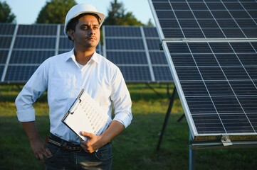 Portrait young indian technician or manager wearing formal cloths standing with solar panel....