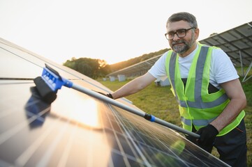 Worker cleaning solar panels after installation outdoors.