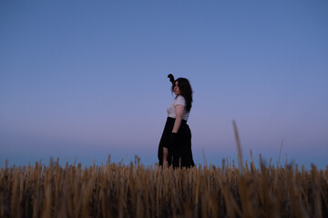 Mujer joven estilo gótica posando en el campo durante el atardecer