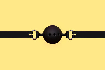 Black BDSM gag on a yellow background. Sex toys. Sex shop concept. BDSM - outfit for adult sex games - obrazy, fototapety, plakaty
