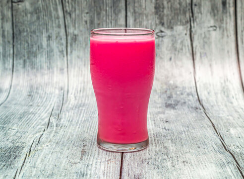 rose milk served in glass isolated on wooden table top view of indian healthy drink