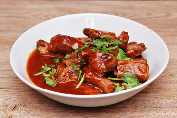 Chinese Red Soup Pork Ribs served on a white plate, a popular Chinese dish, made from sliced pork ribs and tomato sauce.