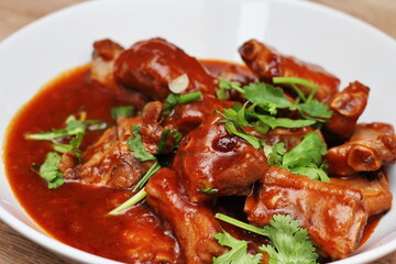 Chinese Red Soup Pork Ribs served on a white plate, a popular Chinese dish, made from sliced pork ribs and tomato sauce.