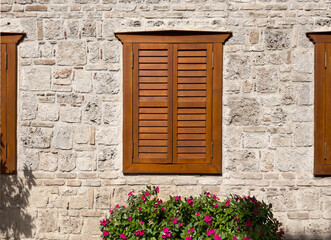 Fototapeta na wymiar Old architecture with wood shutters on ancient window, stone wall