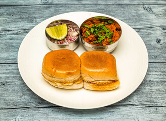 chicken pav bhaji or vada pav bun kabab with lemon and onion served in dish isolated on wooden table top view of indian spicy food