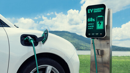 Electric car plugged in with charging station to recharge battery by EV charger cable with nature...