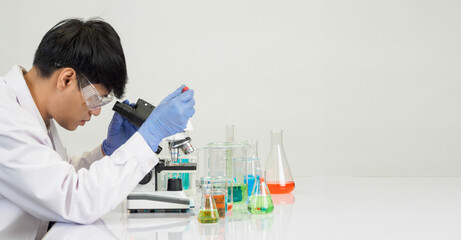 Portrait asian man student scientist Wearing a doctor gown in the lab looking hand at chemist. caused by mixing reagents in scientific research laboratories with test tubes and microscope on the table