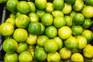 Fresh green limes stacked in a produce bin at a grocery store.