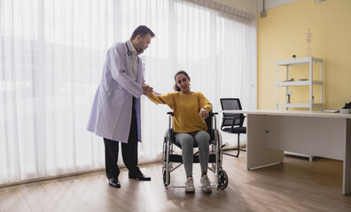 Portrait latin american woman sick sit wheelchair with man doctor caucasian sitting two people...