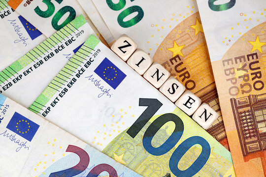 Top view of the German word for interest rates written with wooden letter cubes on various Euro banknotes, concept image for financing or investment with the associated interest