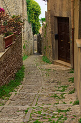 Scenic landscape view of typical narrow pedestrian medieval cobblestone street along ancient buildings in historical part of Erice village, Sicily, Italy. Travel and tourism concept