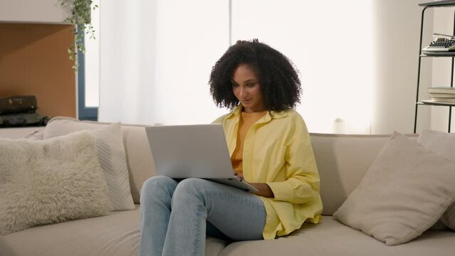 Focused African american girl freelancer ethnic woman working with pc laptop on couch young student e-learning study distant education female shopper businesswoman shopping online at home apartment