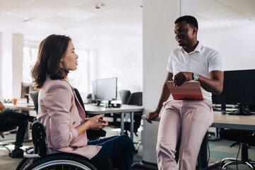 Obraz premium A businesswoman with disability is discussing project with a colleague.