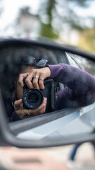 Girl photographing her reflection in the car mirror