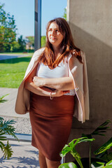 Caucasian businesswoman standing by wall in sunny office. Young serious boss manager having break....
