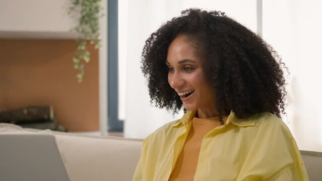 Shocked amazed African American ethnic happy girl 20s woman surprised good news amazement work at home office with laptop computer win job offer success ecstatic achievement victory online discounts