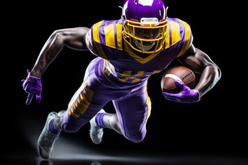 Portrait of American football player running with the ball. Muscular athlete in a purple and yellow uniform with an ovoid ball in a dynamic pose. Isolated on black background.