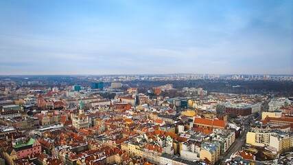 Naklejka premium Aerial view of Poznan's historic market square in winter, showcasing the charming old townhouses adjacent to the square. The drone captures the city's architectural heritage under a winter sky.