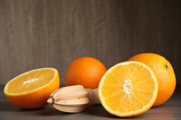Fresh ripe oranges and reamer on wooden table