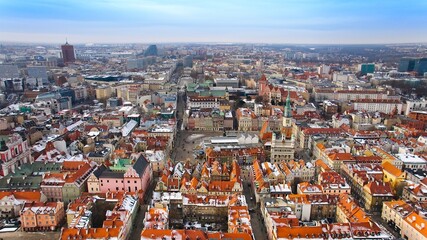 Aerial view of Poznan's historic market square in winter, showcasing the charming old townhouses adjacent to the square. The drone captures the city's architectural heritage under a winter sky.