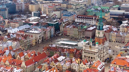 Fototapeta na wymiar Aerial view of Poznan's historic market square in winter, showcasing the charming old townhouses adjacent to the square. The drone captures the city's architectural heritage under a winter sky.