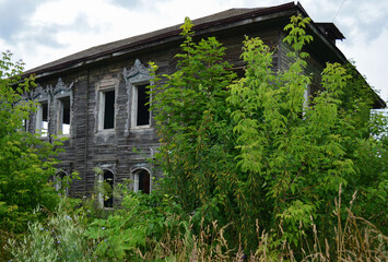 An abandoned wooden old house, gray boards, bushes. weeds, a mystical view.