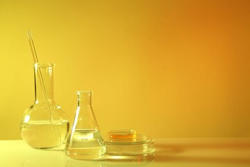 Laboratory analysis. Different glassware on table against yellow background, space for text