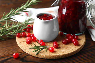 Cranberry sauce, fresh berries and rosemary on wooden table