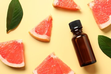 Flat lay composition with grapefruit essential oil on pale yellow background