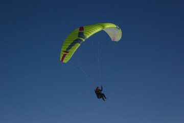 yellow paraglider. Person who paraglides. Paragliding in a blue sky