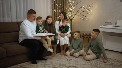 A father reads the bible while sitting on the sofa at home with his extended family
