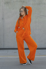young lady in sunglasses and orange pantsuit outdoors