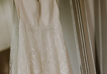 Close up of a white lacy wedding dress hanging on a mirror