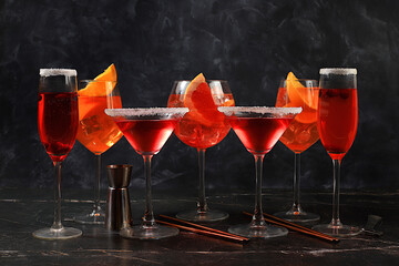 Assortment of alcoholic cocktail Aperol spritz, champagne and red martini in glasses on a dark...
