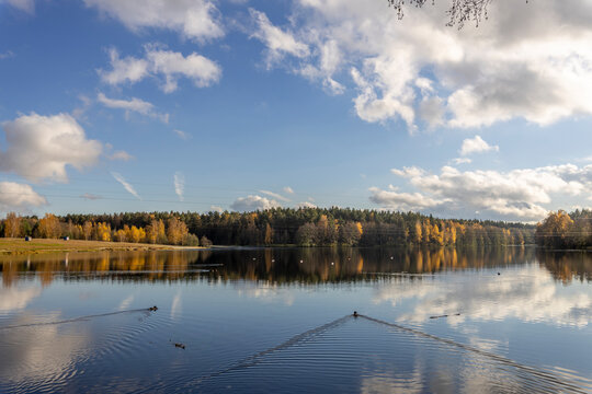 Clouds are reflected in the river, Autumn landscape with a river and trees along the shore. - Powered by Adobe