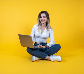 Naklejka premium Woman hold use laptop, full body young cheerful caucasian woman hold use laptop. Sit floor legs crossed. Wearing white shirt, causal denim jeans white sneakers. People lifestyle concept. 