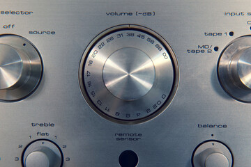 Macro of a vintage amplifier, and its volume dial in decibels. Other knobs for controlling it can be seen around it.