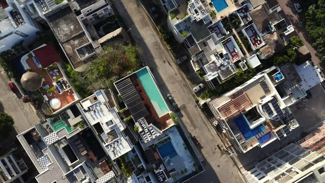 Drone top down view of streets in Playa del Carmen with rooftop swimming pools and soft light of the sunrise 