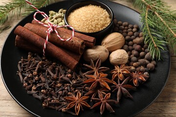 Dishware with different spices and fir branches on table, closeup