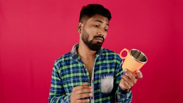 Man in plaid shirt holding orange object with skeptical expression on pink background