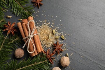 Different spices, nuts and fir branches on gray table, flat lay. Space for text
