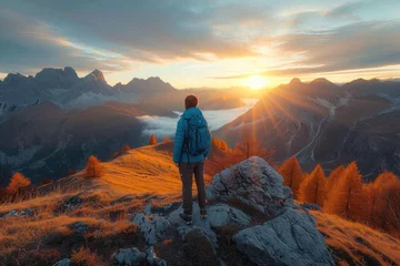 Foto op Plexiglas As the sun rises over the rugged autumn landscape, a solitary figure stands atop a rocky peak, surrounded by vast skies and endless wilderness © Pinklife