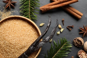 Different aromatic spices and fir branches on dark textured table, flat lay