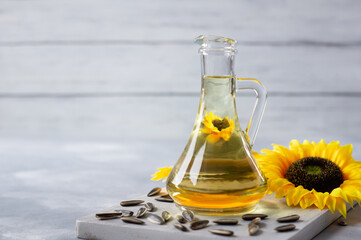 Obraz na płótnie Canvas Glass bottle of sunflower seed oil with flowers on white rustic background, cooking oil, helianthus annuus