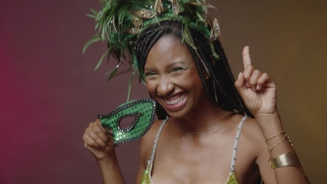 Brazilian woman in green carnival clothes, with mask close-up dancing