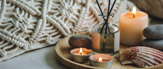 Apartment natural aroma diffusor with sea breeze fragrance. Burning candles on bamboo tray, cozy home atmosphere. Relaxation, detention zone in the living or bedroom. Stones as decor. Banner
